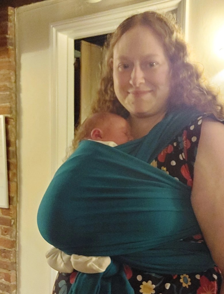 2 day old baby in stretchy wrap with feet out